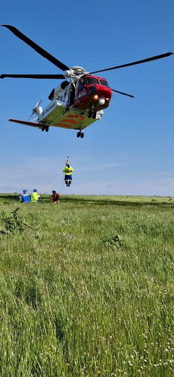 Samuel Thomsen suspended mid air underneath a HM Coastguard Helicopter